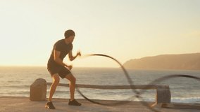 Athletic man fitness model training battle rope against sea during sunset. Sport fitness healthy lifestyle concept. Caucasian person muscular body functional training endurance. - Powered by Shutterstock - Get 15% off with code: PIKWIZARD15