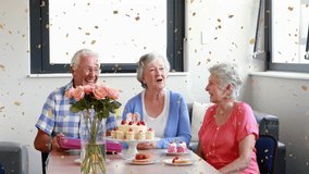 Confetti animation over elderly friends celebrating birthday with gifts and cupcakes. Celebration, party, fun, happiness, joy - Powered by Shutterstock - Get 15% off with code: PIKWIZARD15