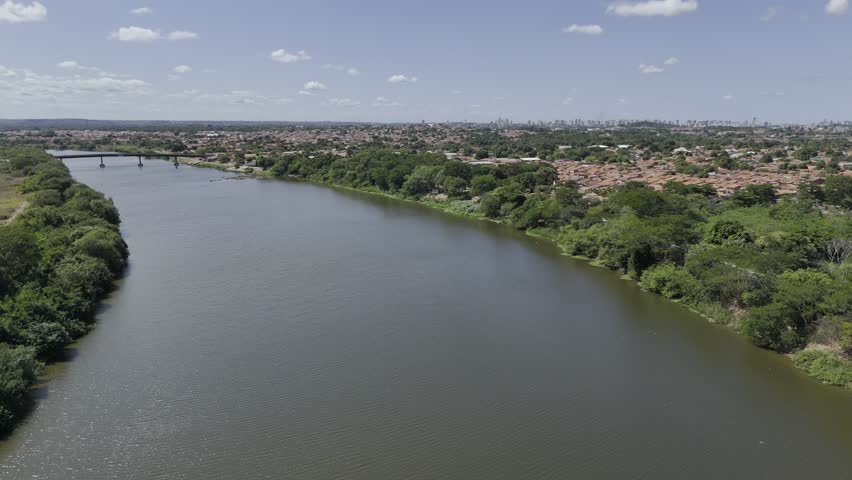 Drone flies backwards over Poti River toward the Meeting of the Rivers on sunny afternoon with Parnaíba River in Teresina, Piauí, Brazil
