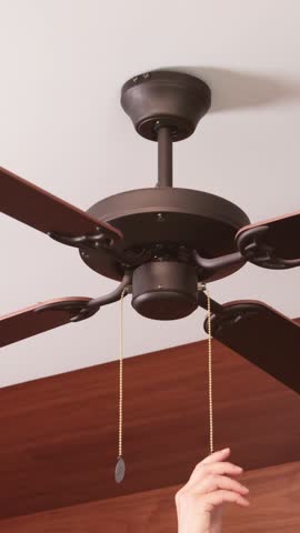 Anonymous turn on wooden ceiling fan. Modern device for cooling room with variable speed control. Summer and heat.