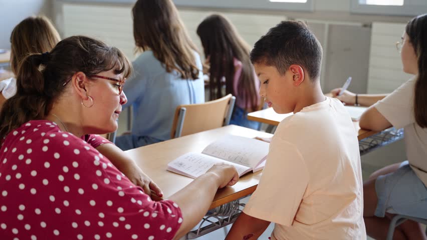Young Teacher helping hispanic student boy to understand homework exercise at primary school classroom - Powered by Shutterstock - Get 15% off with code: PIKWIZARD15