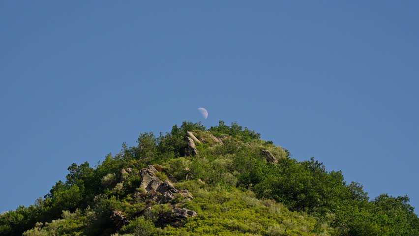 Crescent moon over mountain top in the afternoon