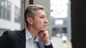 Thoughtful pensive businessman in a suit stands lost in thought, his hand on his chin. Man appears contemplative and serious, perhaps reflecting on a work challenge or decision. - Powered by Shutterstock - Get 15% off with code: PIKWIZARD15