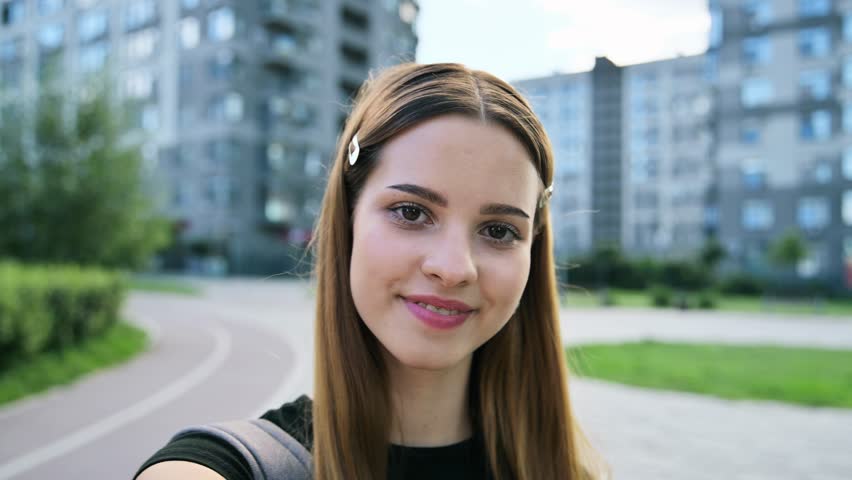 Web camera view of teenage cheerful female, looking at webcam, outdoor