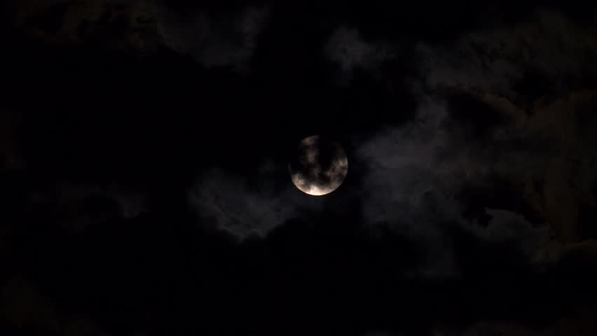 full moon disappearing among the clouds in the night sky, full moon moving among the clouds at night,