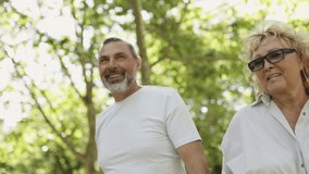 Senior couple walking through sunny park - Powered by Shutterstock - Get 15% off with code: PIKWIZARD15