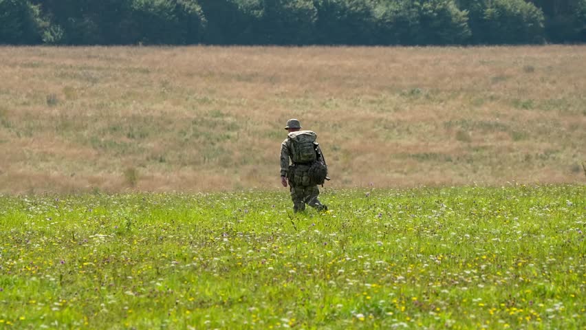 British army soldier tabbing with 25Kg bergen and rifle across open countryside, Wiltshire UK