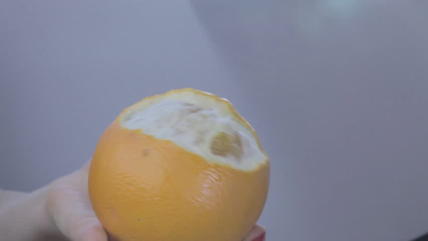 Hands of young woman peel orange. Orange fruit splashes are fountaining to air