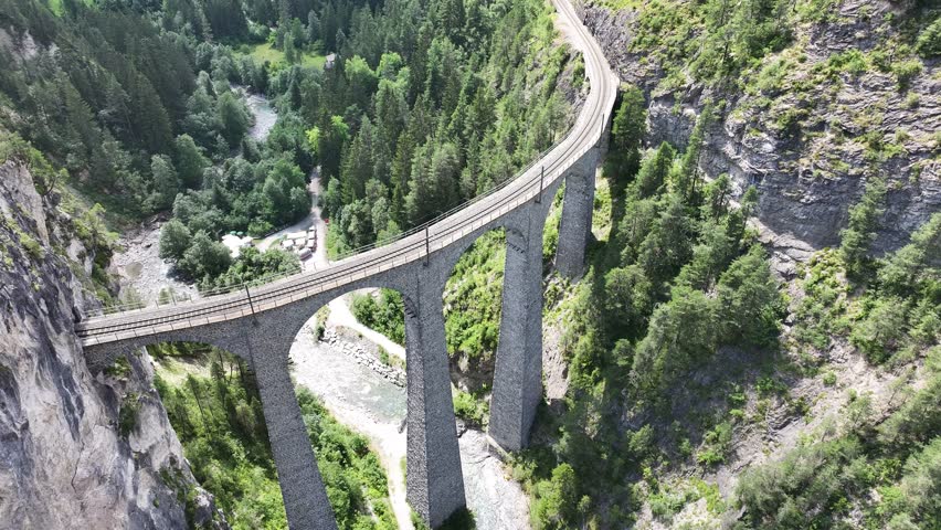 Landwasser Viaduct curving over deep valley surrounded by dense forests in Filisur and Schmitten, Graubünden, Switzerland