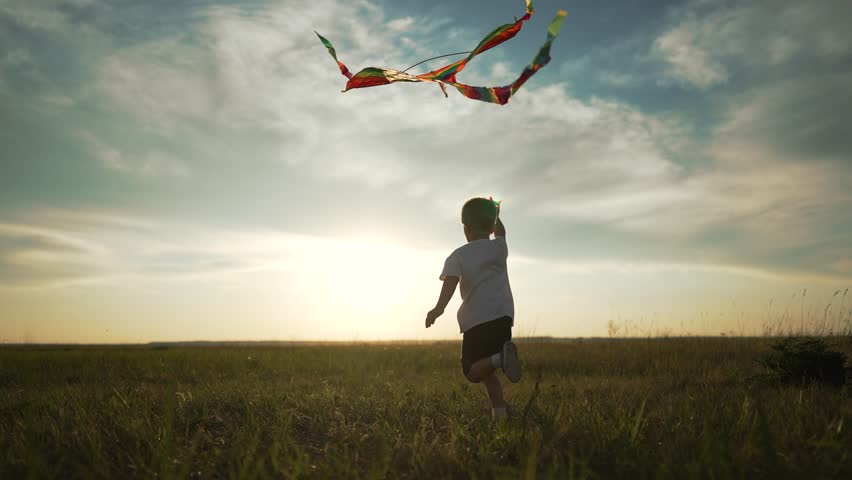 Child flying on grass. child playing with kite outdoors. kid running in open field with kite. Child fun outdoor activity with kite. Scenic grassy meadow at sunset. Child enjoying kite flying on grass.