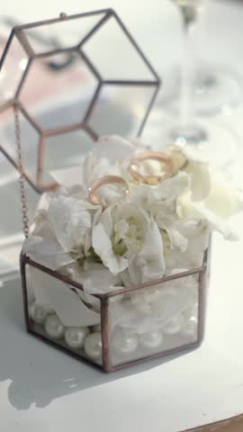 close-up of the wedding rings of the bride and groom before the outdoor ceremony lie on the table, champagne glasses