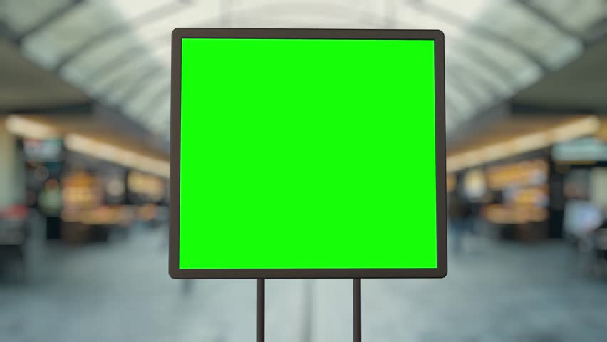 Digital signage billboard with a green screen is showing a timelapse of an airport with travelers and employees walking by