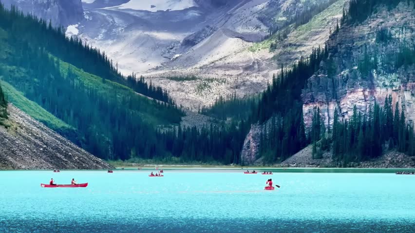 A serene view of Lake Louise, Alberta, Canada, showcases vibrant turquoise waters framed by towering, pine-covered mountains, with distant canoers paddling peacefully across the lake.