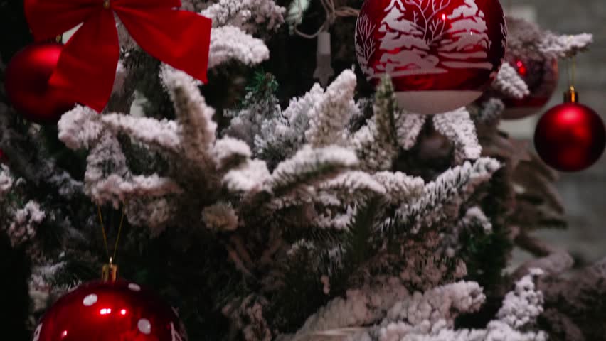 Young Couple Decorating a Christmas Tree with Crystal Globe Ornaments, A heartwarming scene of a young woman and her partner decorating a Christmas tree in their living room, carefully placing crystal