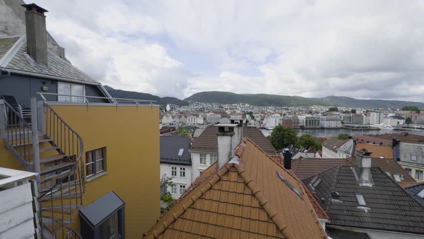 Scenic establishing pan over Bergen, showcasing the charming rooftops and Norwegian architecture in the city center