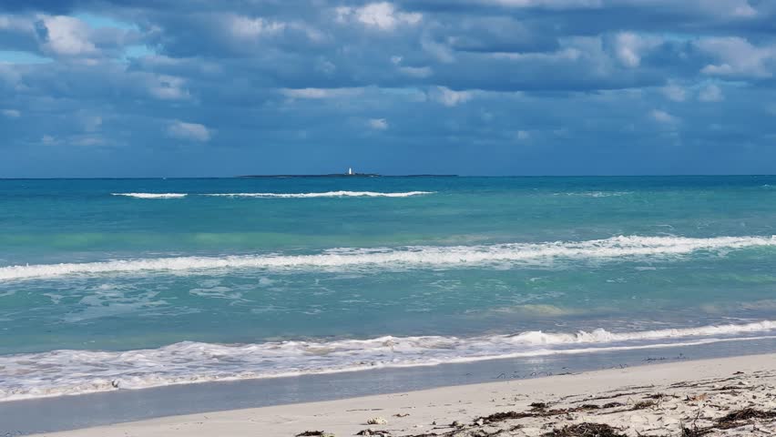 A beautiful Cuban beach in Varadero, Cuba, where you can see the waves and ocean waters on a cloudy day with the sun breaking through the clouds. Turquoise waves. 4K Video