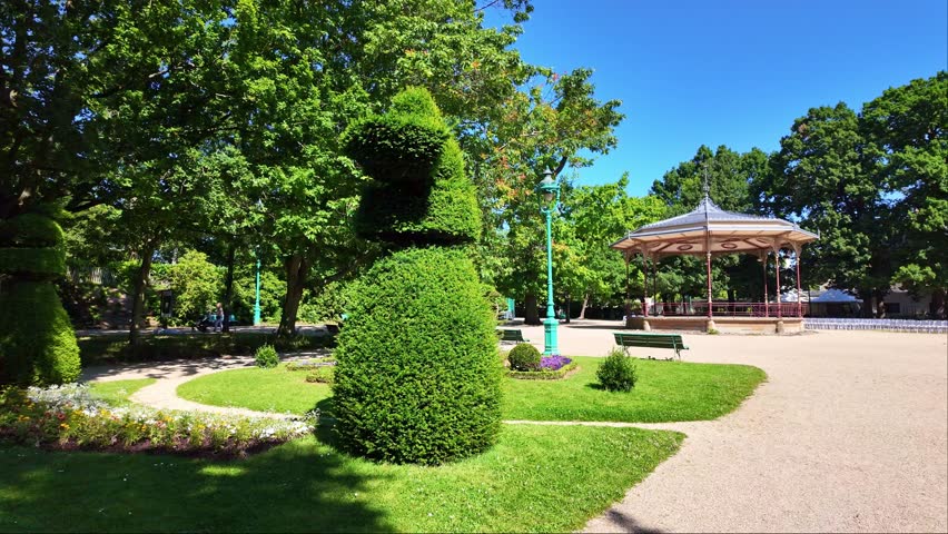 Part view at summer in the famous and public Thabor Park or Parc du Thabor with bandstand in background, Rennes, France. First-person walking backward