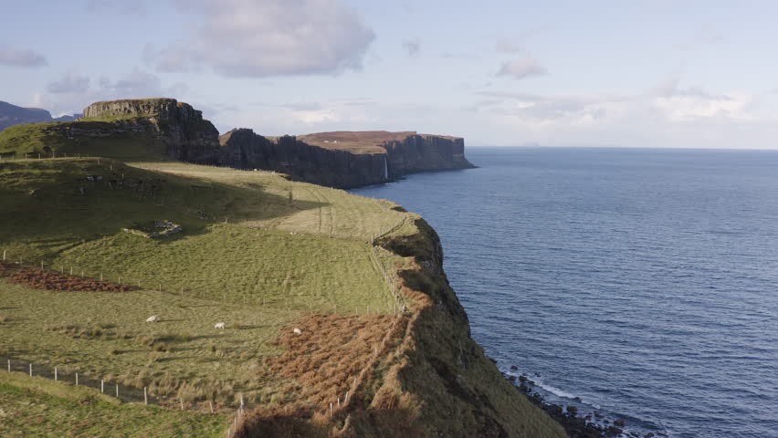 Sheep farm alongside cliff edge in Isle of Skye by the stunning sea cliffs with Mealt Falls and Kilt Rock in the distance