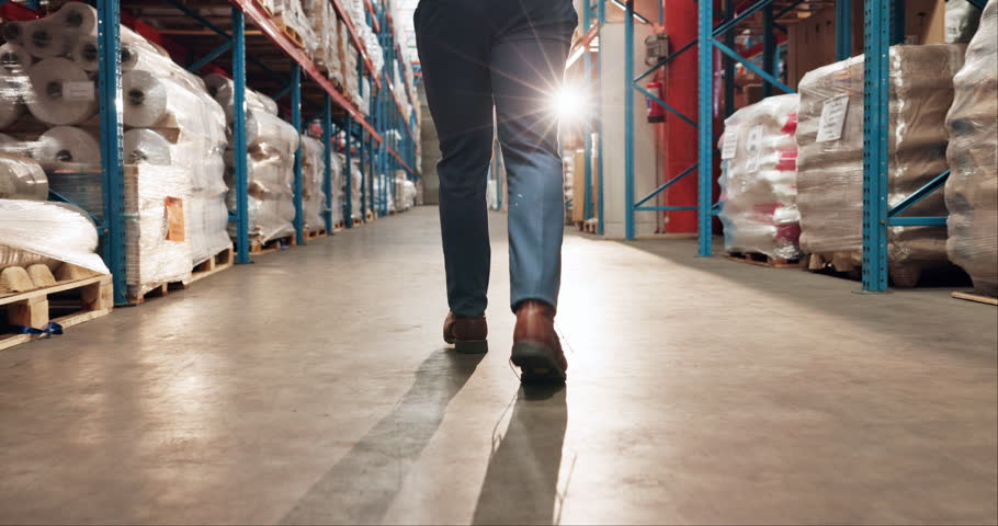 Man, legs or walking in warehouse for storage, food distribution or wholesale production. Back, factory worker and footsteps of supply chain supervisor in inspection, logistics or industrial shipping