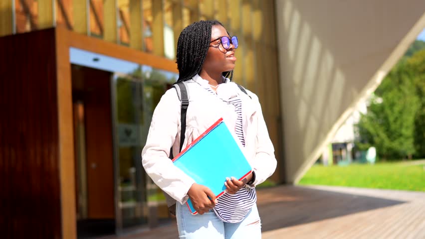 Proud african female student walking outside the university in a sunny day of spring