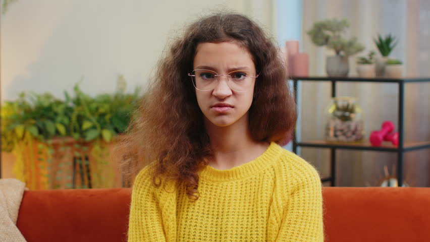 Dislike. Upset child girl showing thumbs down sign gesture, expressing discontent, disapproval, dissatisfied bad work at modern home apartment indoors. Displeased teenager 14-15 years kid in room