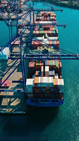 Container ship loading and unloading in sea port, Aerial Vertical video