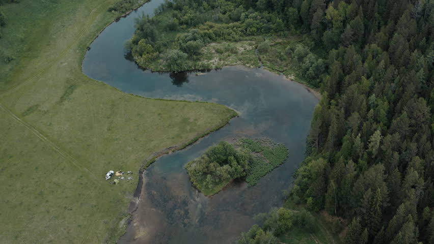 Car trip and camping in the wild. Morning view of the campsite with car and tents set on the river coast in mountains