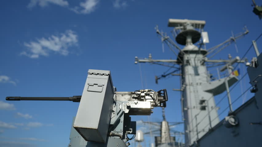 Color image of an automated machine gun on the deck of a military ship, at sea.
