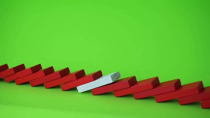 Row of red and white domino falling down against green background. Domino effect.