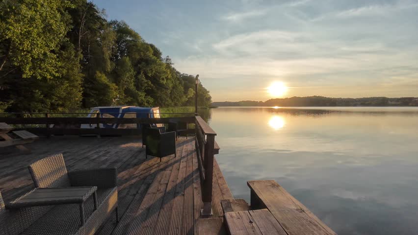 A view on the sunset from a boats pier over a smooth calm surface of a lake