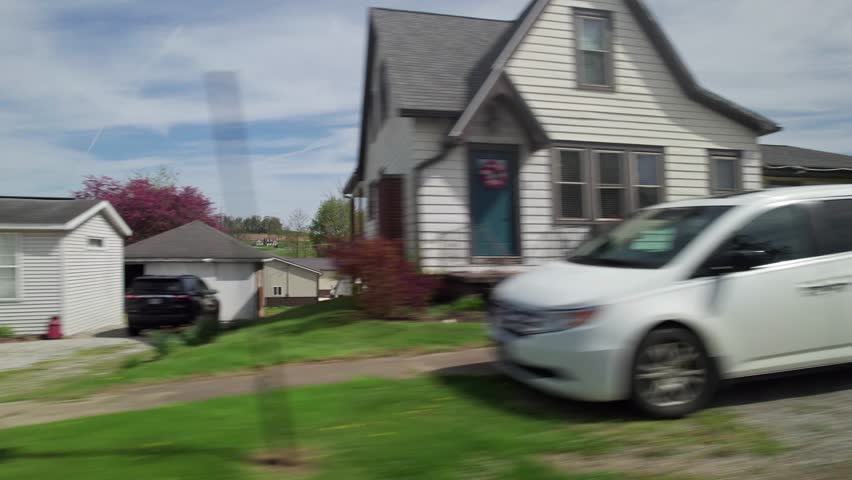 Driving around small town America in Ohio countryside, moving past wood buildings, old barns, farm land, crops, trees, and large fields in conservative rural area outside Columbus and Danville, OH 