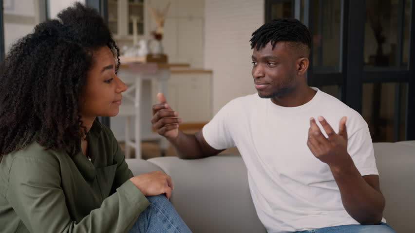 African American love couple friends man woman girl guy male female girlfriend listen boyfriend talking on couch sofa tell story gossip chatting casual conversation talk smiling friendly date at home