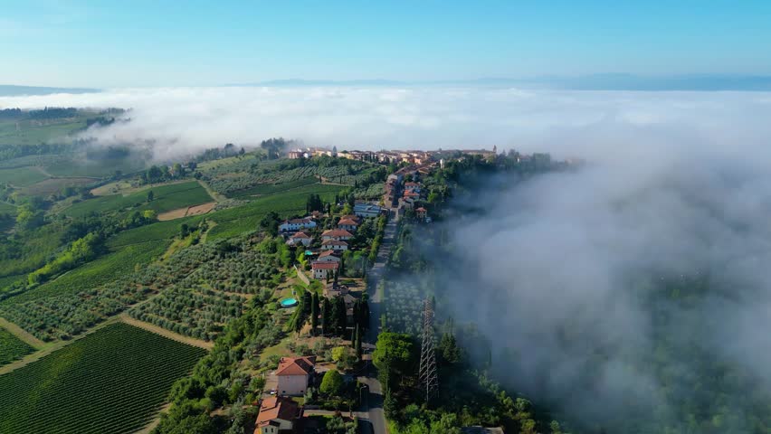 An early morning aerial view of the Tuscan Toscana landscape  near Camping Panorama del Chianti, captured by a drone. The scene is enveloped in a magnificent layer of fog creating a dreamy atmosphere