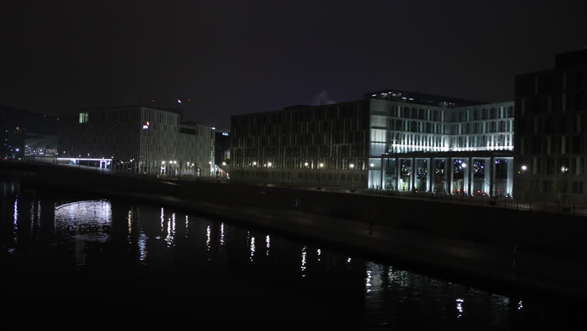 Berlin scene, Urban reflections, Berlin night. Night scene Berlin showcases modern buildings with illuminated facades that reflect beautifully on river.