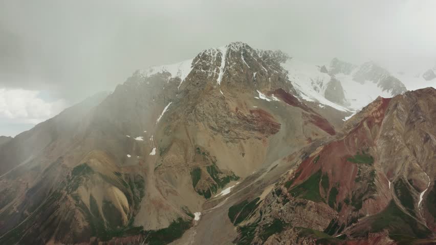 View of Lenin Peak, one of the highest peaks of Central Asia. The Pamir mountain system. Colorful Pamir mountains, mountain ranges, snow-capped peaks, glaciers and hills. Kyrgyzstan. Drone 4K