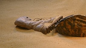 military helmet, a pair of worn combat boots, and a pair of broken sunglasses, partially buried in the sand. The arrangement suggests a narrative of someone having been in this harsh environment - Powered by Shutterstock - Get 15% off with code: PIKWIZARD15