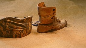 An arrangement of abandoned military gear, including a worn-out boot, helmet, and shattered protective eyewear, partially buried in desert sand, symbolizing the harsh realities of conflict.
 - Powered by Shutterstock - Get 15% off with code: PIKWIZARD15