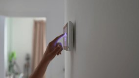 Closeup hand using smart home touch screen with connected appliances device on wall. Setting, checking energy security heating system on digital control in apartment. Home automation monitoring. - Powered by Shutterstock - Get 15% off with code: PIKWIZARD15