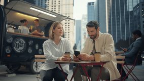 Caucasian Man Showing Information on a Smartphone to His Girlfriend in a Street Cafe. Beautiful Couple Enjoying Outdoors Lunch with Coffee, Browsing Internet and Shopping Online - Powered by Shutterstock - Get 15% off with code: PIKWIZARD15