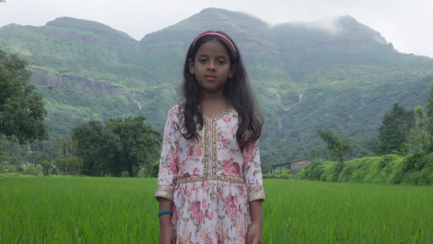 Bhandardara, Maharastra, India- August 11th- 2024- Compact high speed shot of well dressed Indian girl folding hands and giving serious expression towards  the camera.With mountains in background.