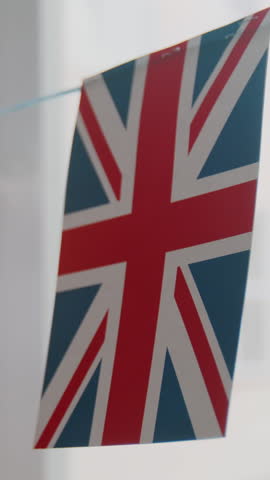 Close-up vertical no people shot of flag of Great Britain, hanging on string, decorating window in foreign languages school or English class, at daytime