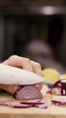 Close-up male hands cutting red onions into slices on a cutting board