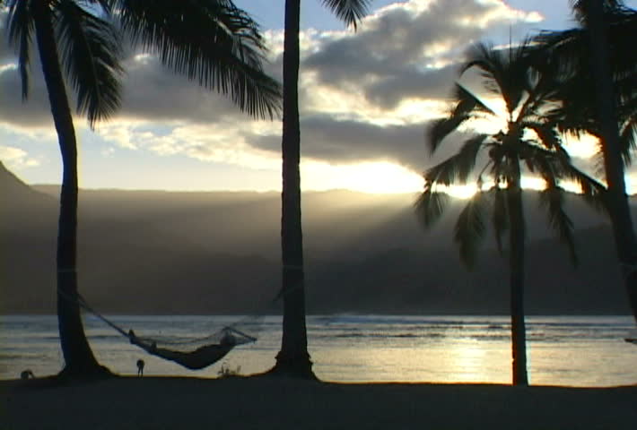 Tourist lays in hammock at dusk in Kauai, Hawaii.