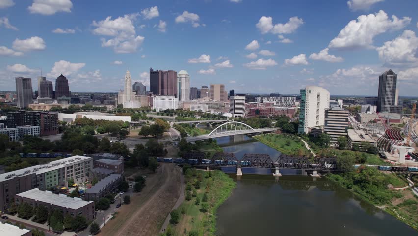 Drone aerial of cityscape, buildings, skyscrapers, and high-rises of capital city of Columbus, Ohio in United States, with new Peninsula and Franklinton construction and homes in the foreground