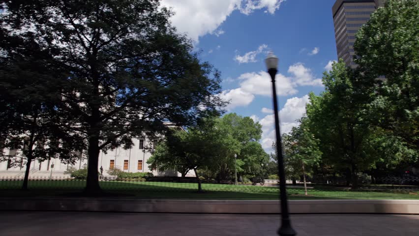 Ohio Statehouse and capitol building in city center of Columbus, OH as car drives by, with historic and political significance with architecture, legislation, statues, and governor of Midwest State