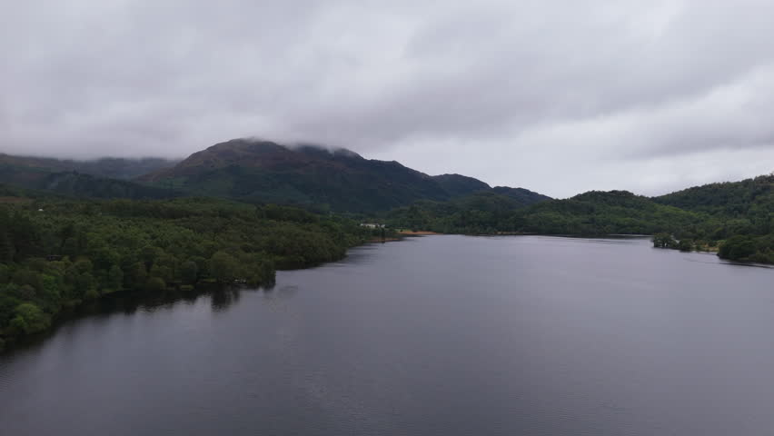 Aerial view over Loch Achray in Scotland with mountain in background on cloudy day