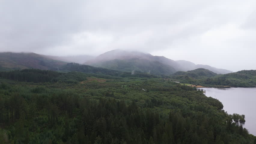 Aerial view over Loch Achray in Scotland with mountain in background on cloudy day