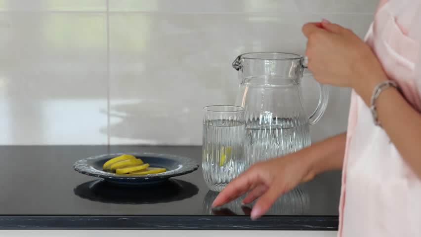 woman in kitchen in the morning drinking water with lemon,coffee,eating waffles with cranberries. girl in pajamas arranging flowers in vase, relax and chill.female enjoy time preparing breakfast.