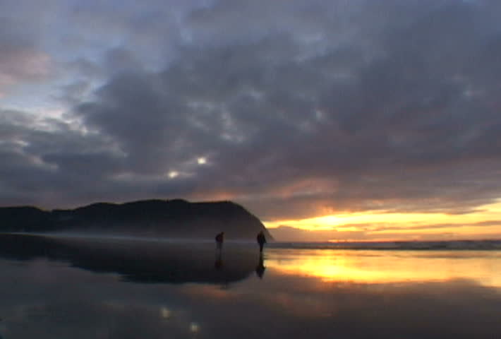 Two people walk during sunset in Seaside, Oregon