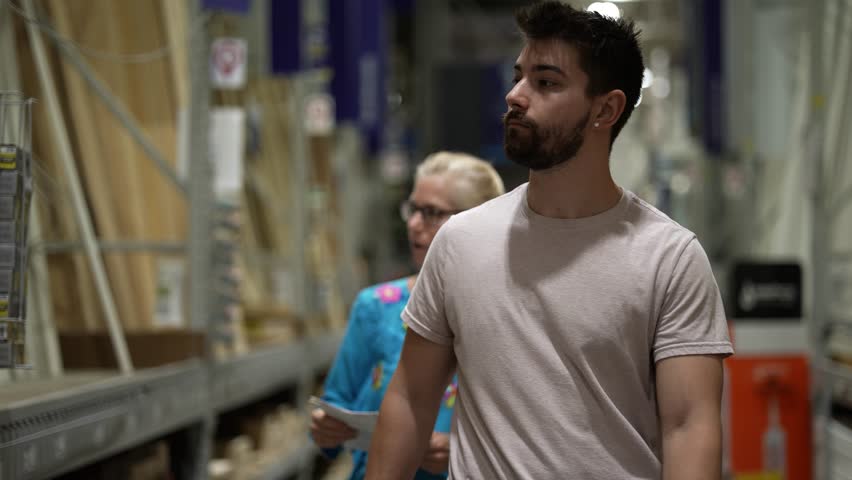 Man and woman looking inspecting and shopping for wood lumber construction supplies in hardware store.